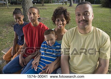 Portrait of cheerful family sitting on the bench at park View Large Photo Image Stock Image - Portrait of cheerful family sitting on the bench at park. Fotosearch