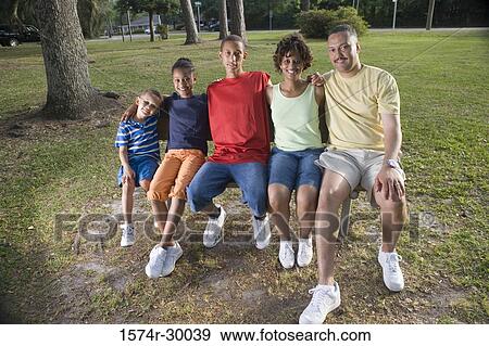 Portrait of cheerful family sitting on the bench at park View Large Photo Image Stock Photo - Portrait of cheerful family sitting on the bench at park. Fotosearch