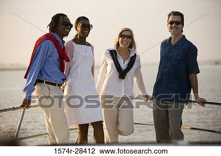 Stock Image - Portrait of cheerful friends leaning against railing. Fotosearch