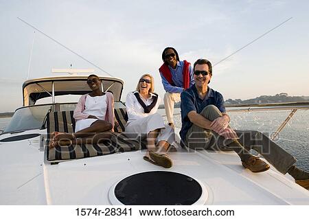 Stock Image - Portrait of cheerful friends relaxing on the deck of a boat. Fotosearch