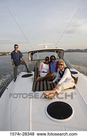Stock Photo - Portrait of cheerful friends relaxing on the deck of a boat. Fotosearch