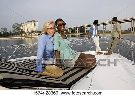 Stock Photo - Portrait of cheerful friends relaxing on the deck of a boat. Fotosearch