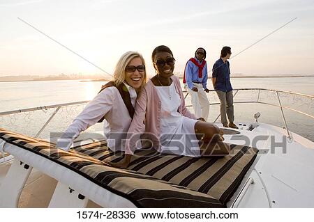 Stock Photograph - Portrait of cheerful friends relaxing on the deck of a boat. Fotosearch