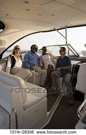Stock Photograph - Portrait of cheerful friends sitting in the boat. Fotosearch