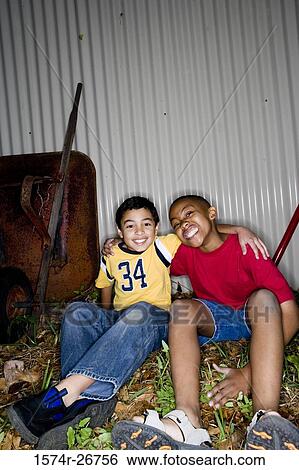 Stock Photograph - Portrait of cheerful friends sitting with arm around by push cart. Fotosearch