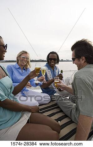 Portrait of cheerful friends toasting champagne on the deck of a boat View Large Photo Image Picture - Portrait of cheerful friends toasting champagne on the deck of a boat. Fotosearch