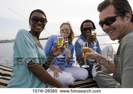 Portrait of cheerful friends toasting champagne on the deck of a boat View Large Photo Image Stock Photography - Portrait of cheerful friends toasting champagne on the deck of a boat. Fotosearch