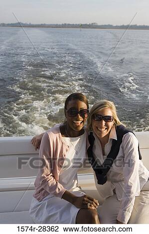 Portrait of cheerful mid adult women wearing sunglasses in the boat View Large Photo Image Stock Image - Portrait of cheerful mid adult women wearing sunglasses in the boat. Fotosearch