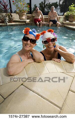 Portrait of cheerful senior women in swimming pool while senior men sitting on poolside View Large Photo Image Stock Photo - Portrait of cheerful senior women in swimming pool while senior men sitting on poolside. Fotosearch