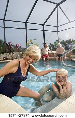 Portrait of cheerful senior women poolside while senior men discussing in the background View Large Photo Image Picture - Portrait of cheerful senior women poolside while senior men discussing in the background. Fotosearch