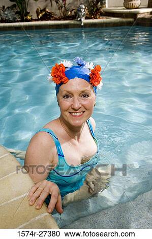 Stock Image - Portrait of cheerful senior women sitting in swimming pool. Fotosearch