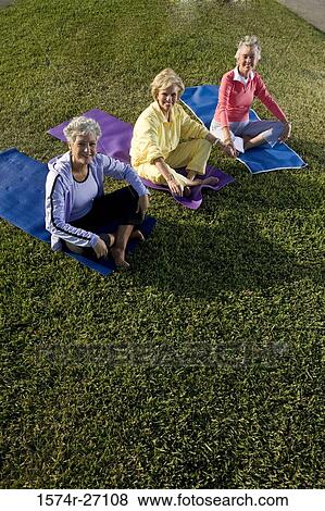 Stock Photo - Portrait of cheerful senior women sitting on exercise mat and meditating. Fotosearch