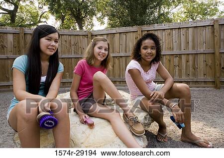 Portrait of cheerful teenage girls sitting on the rock in the petting zoo View Large Photo Image Picture - Portrait of cheerful teenage girls sitting on the rock in the petting zoo. Fotosearch