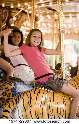 Portrait of cheerful teenage girls sitting on a carousel and waving hands View Large Photo Image Stock Photo - Portrait of cheerful teenage girls sitting on a carousel and waving hands. Fotosearch