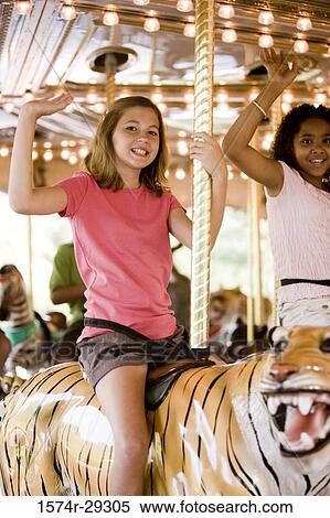 Portrait of cheerful teenage girls sitting on a carousel and waving hands View Large Photo Image Stock Photography - Portrait of cheerful teenage girls sitting on a carousel and waving hands. Fotosearch