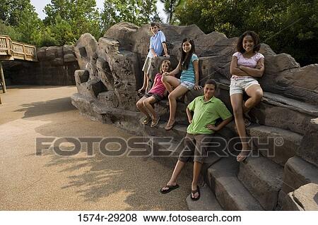 Stock Photo - Portrait of cheerful teenagers sitting on rocks. Fotosearch