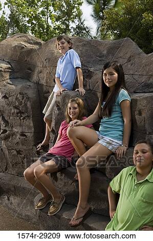 Portrait of cheerful teenagers sitting on rocks View Large Photo Image Stock Photo - Portrait of cheerful teenagers sitting on rocks. Fotosearch