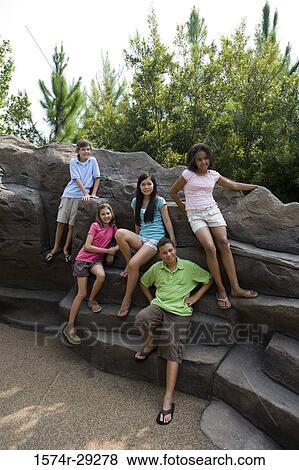 Portrait of cheerful teenagers sitting on rocks View Large Photo Image Stock Photo - Portrait of cheerful teenagers sitting on rocks. Fotosearch