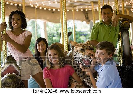 Stock Photo - Portrait of cheerful teenagers standing in a carousel. Fotosearch