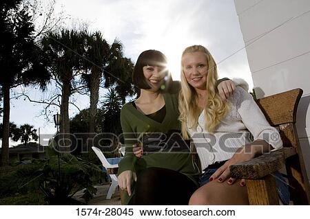 Stock Photography - Portrait of cheerful women sitting on armchair. Fotosearch