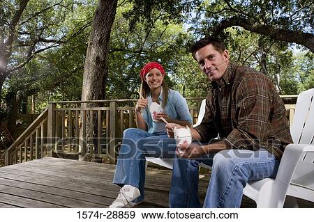 Portrait of cheerful young couple sitting together and eating View Large Photo Image Stock Photo - Portrait of cheerful young couple sitting together and eating. Fotosearch