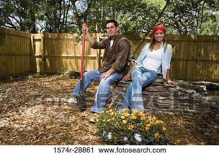 Portrait of cheerful young woman smiling while young man holding shovel View Large Photo Image Stock Image - Portrait of cheerful young woman smiling while young man holding shovel. Fotosearch