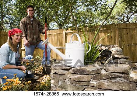 Portrait of cheerful young woman holding plant while young man standing with shovel View Large Photo Image Stock Photography - Portrait of cheerful young woman holding plant while young man standing with shovel. Fotosearch