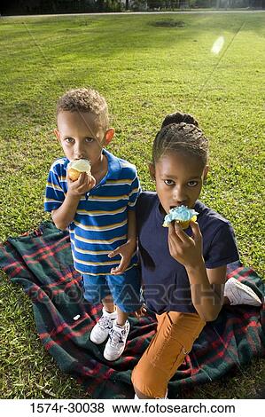 Portrait of children eating pastries on blanket at park View Large Photo Image Stock Photo - Portrait of children eating pastries on blanket at park. Fotosearch