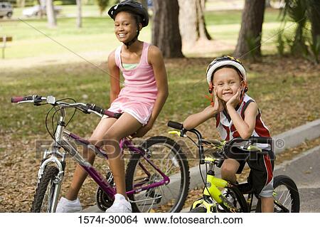 Picture - Portrait of children sitting on bicycle on the road. Fotosearch