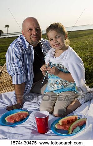Stock Photography - Portrait of father and daughter sitting on a blanket and smiling. Fotosearch