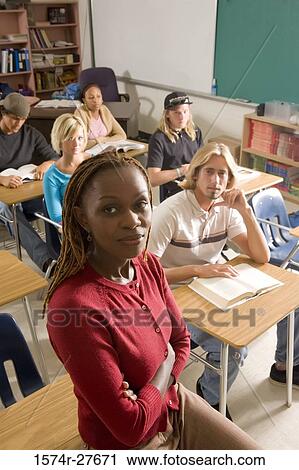 Portrait of female teacher with arms crossed while students reading book View Large Photo Image Stock Image - Portrait of female teacher with arms crossed while students reading book. Fotosearch