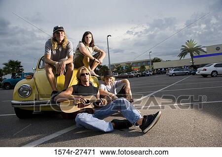 Portrait of friends enjoying music by a car at the parking area View Large Photo Image Stock Image - Portrait of friends enjoying music by a car at the parking area. Fotosearch