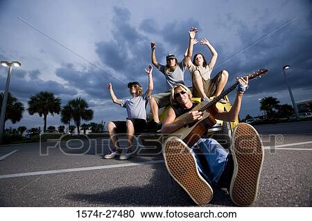 Portrait of friends enjoying music by a car at the parking area View Large Photo Image Stock Image - Portrait of friends enjoying music by a car at the parking area. Fotosearch