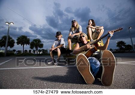 Portrait of friends enjoying music by a car at the parking area View Large Photo Image Stock Photo - Portrait of friends enjoying music by a car at the parking area. Fotosearch