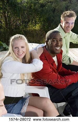 Portrait of friends sitting on armchairs on wooden deck View Large Photo Image Stock Image - Portrait of friends sitting on armchairs on wooden deck. Fotosearch