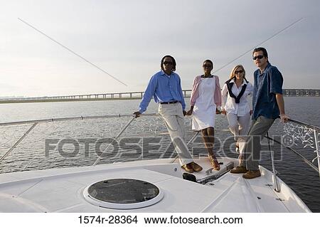 Picture - Portrait of friends standing at bow of a boat. Fotosearch