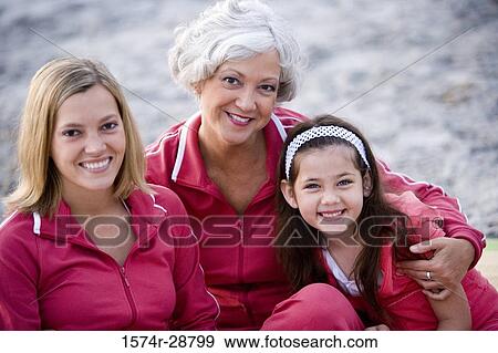 Stock Photo - Portrait of grandmother with her daughter and granddaughter sitting at the beach. Fotosearch