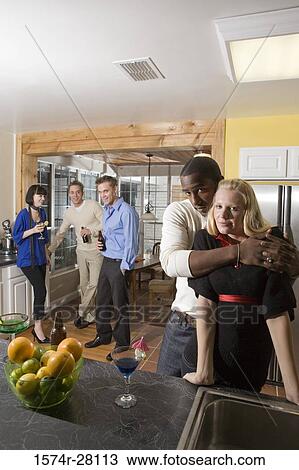 Portrait of man embracing woman in domestic kitchen while their friends standing in background View Large Photo Image Stock Image - Portrait of man embracing woman in domestic kitchen while their friends standing in background. Fotosearch