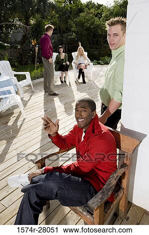 Portrait of men by wall while their friends discussing in background View Large Photo Image Stock Image - Portrait of men by wall while their friends discussing in background. Fotosearch
