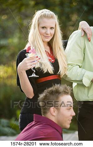 Portrait of mid adult woman holding wineglass and standing with arm around by a young View Large Photo Image Stock Image - Portrait of mid adult woman holding wineglass and standing with arm around by a young. Fotosearch