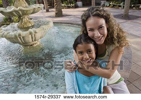 Portrait of mother and daughter sitting together by water fountain View Large Photo Image Stock Photo - Portrait of mother and daughter sitting together by water fountain. Fotosearch