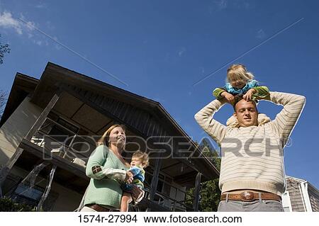 Picture - Portrait of parents holding their children in front of a house. Fotosearch