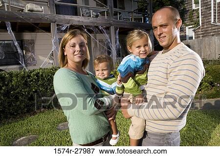 Portrait of parents holding their children in front of a house View Large Photo Image Stock Photo - Portrait of parents holding their children in front of a house. Fotosearch