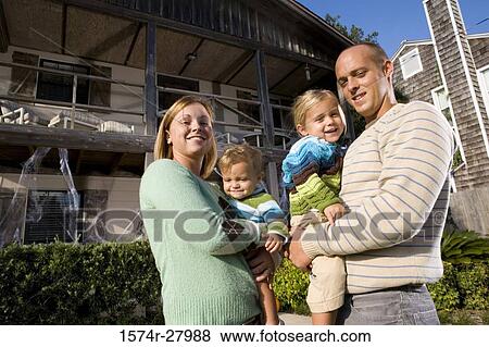Portrait of parents holding their children in front of a house View Large Photo Image Stock Photo - Portrait of parents holding their children in front of a house. Fotosearch