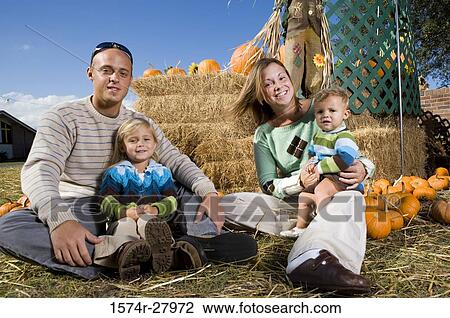 Portrait of parents with their children sitting by straw bundle View Large Photo Image Stock Image - Portrait of parents with their children sitting by straw bundle. Fotosearch