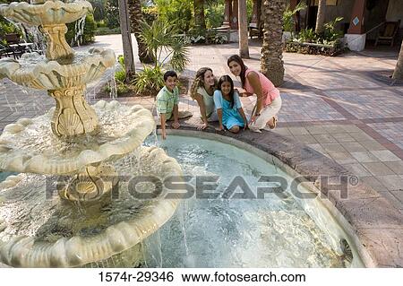 Stock Photograph - Portrait of people sitting together by a water fountain. Fotosearch