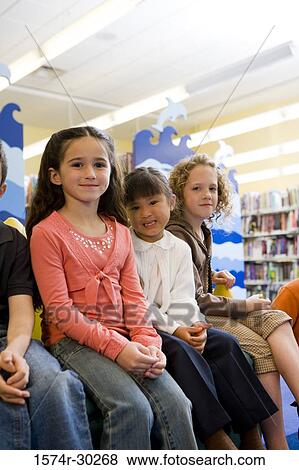 Stock Photo - Portrait of schoolboys and girls sitting together in the library. Fotosearch