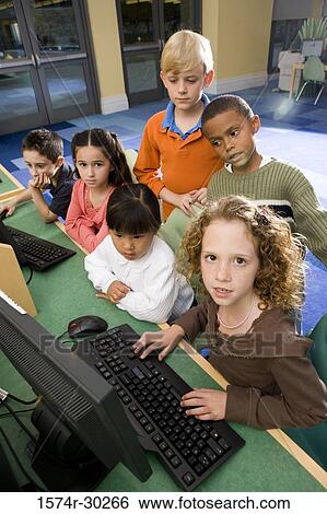 Stock Photograph - Portrait of schoolgirls and boys using computer in the library. Fotosearch