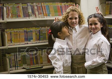 Portrait of schoolgirls showing victory sign over each other's head in the library View Large Photo Image Stock Image - Portrait of schoolgirls showing victory sign over each other's head in the library. Fotosearch