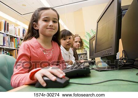 Picture - Portrait of schoolgirls using computer in the library. Fotosearch